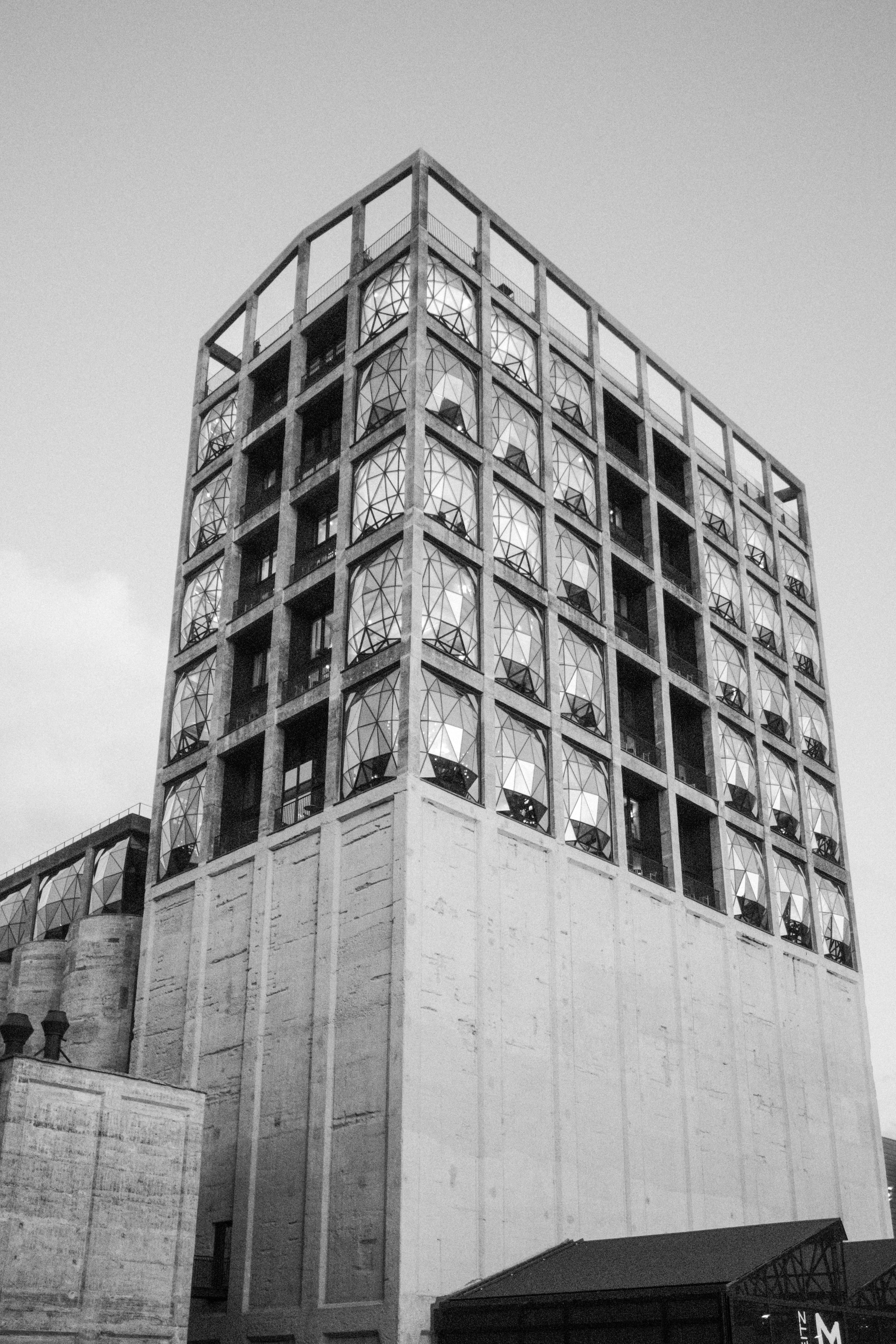Tall concrete building featuring a grid of bulging, faceted geometric windows in black and white.